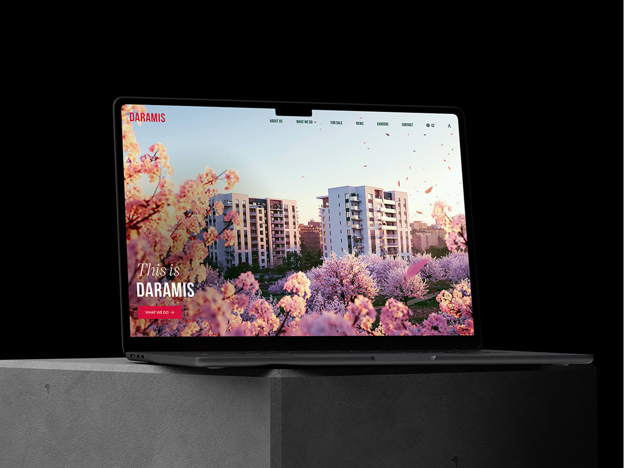 Notebook na betonovém podkladu zobrazuje webovou stránku s květinovou grafikou a nápisem This is Daramis. Elegantní design a moderní architektura na monitoru.