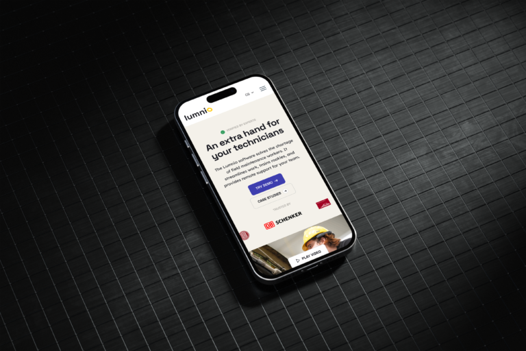 Smartphone ležící na tmavém povrchu s otevřenou aplikací. Displej zobrazuje text nabízející podporu technikům. Úvodní obrazovka obsahuje různé možnosti navigace.
