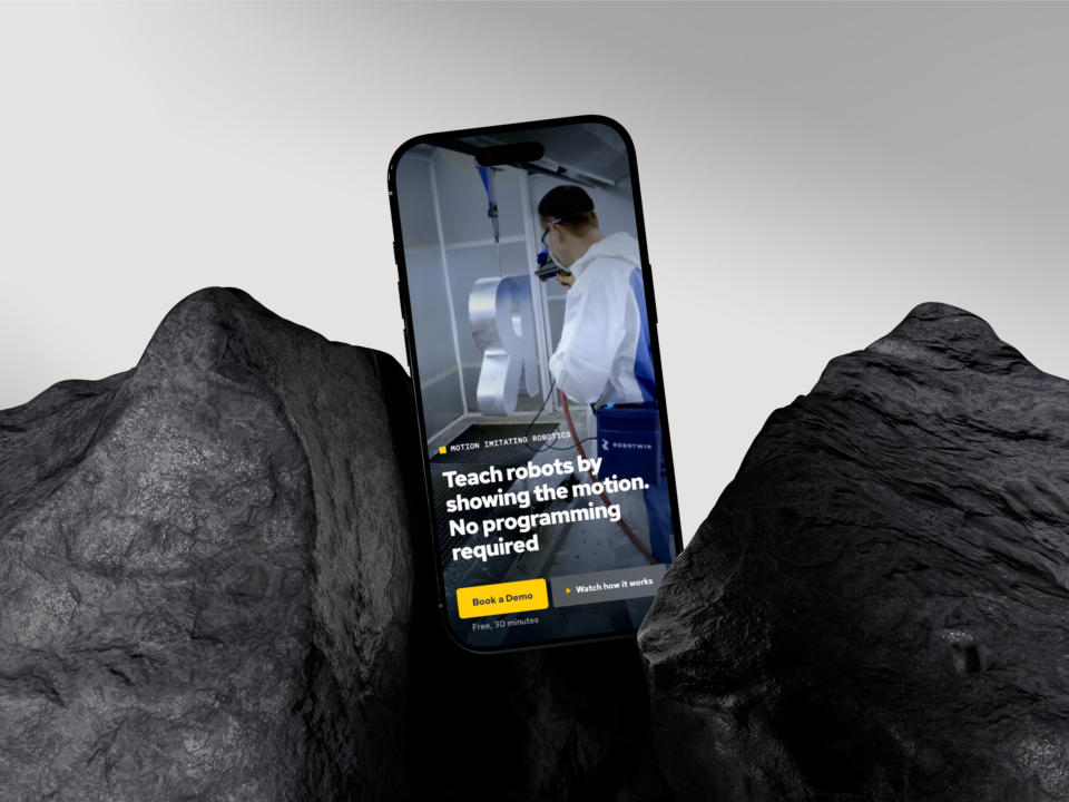 Mobilní web RoboTwin s technikem, který učí robota pohybem, mezi tmavými skalními útvary