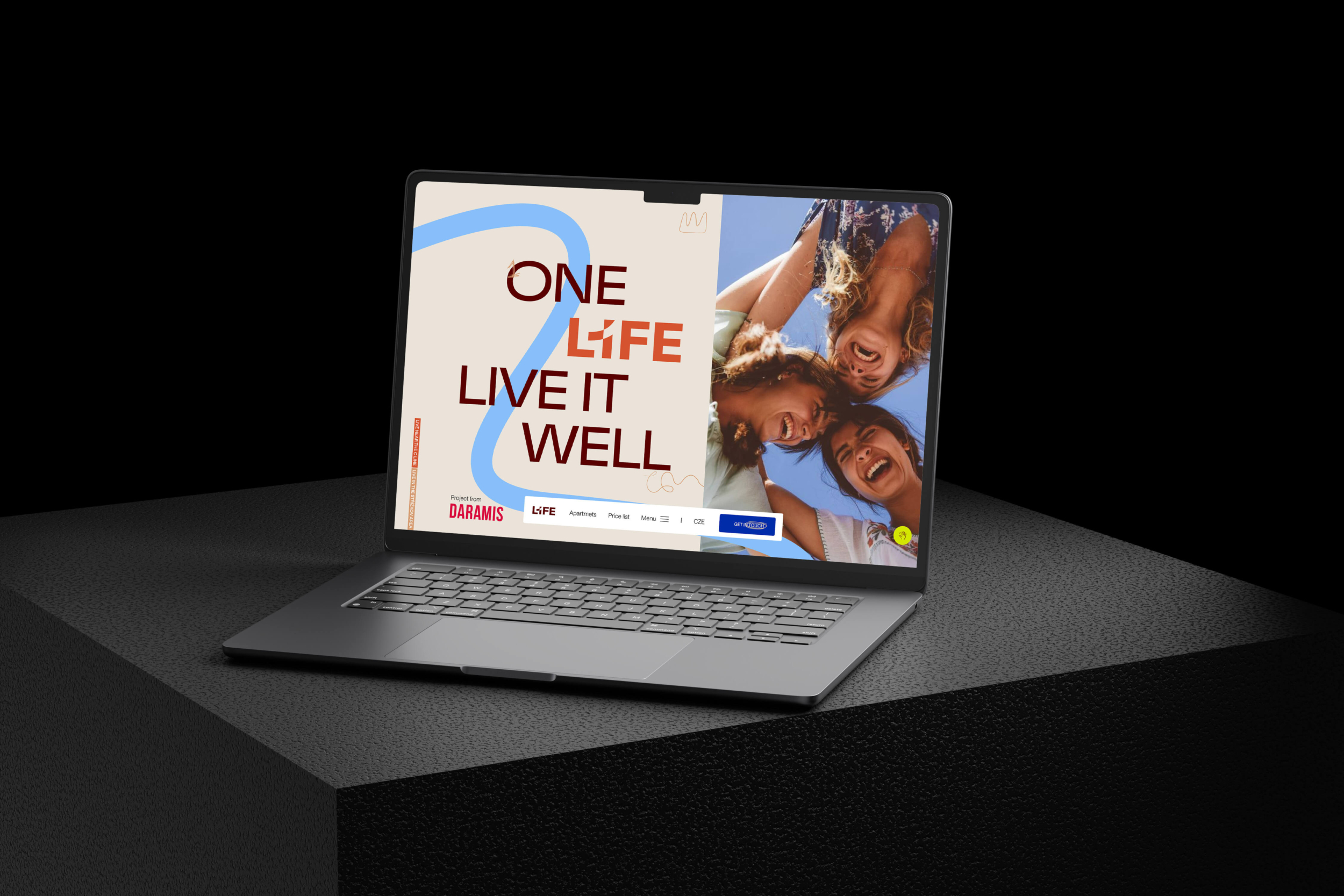A laptop with its screen open on a black background displays the motivational phrase "One Life Live It Well" with an image of three smiling people in the upper corner.