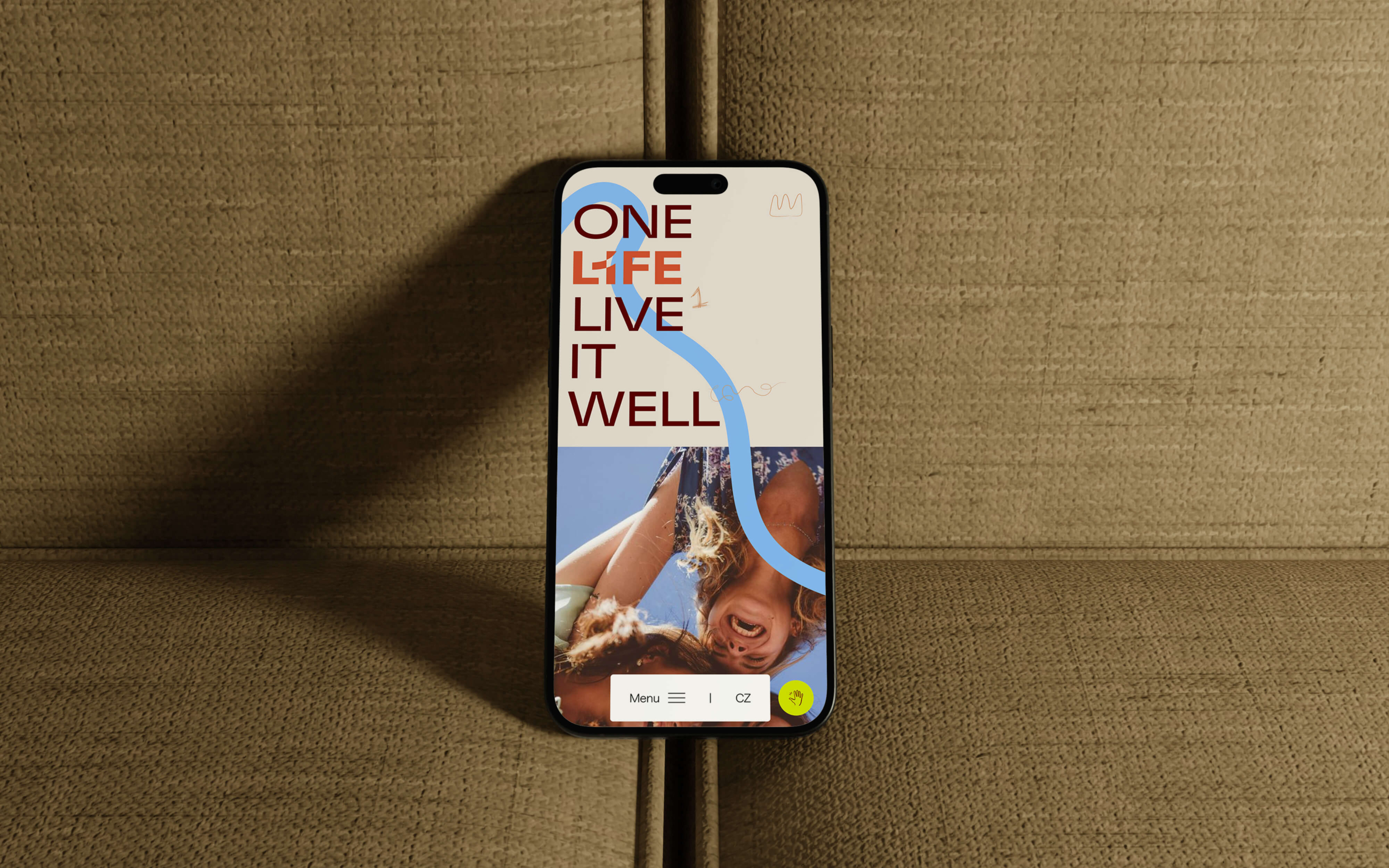 A modern smartphone with the motivational phrase "One Life Live It Well" displayed on its screen, resting on a brown fabric background. A stylish design and an inspiring message on the phone.