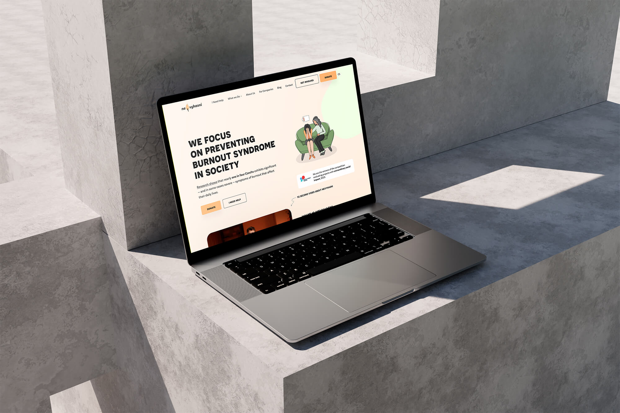 A silver laptop on a concrete surface displays a website dedicated to preventing burnout in the workplace. A diagonal view of the screen in a sunny spot