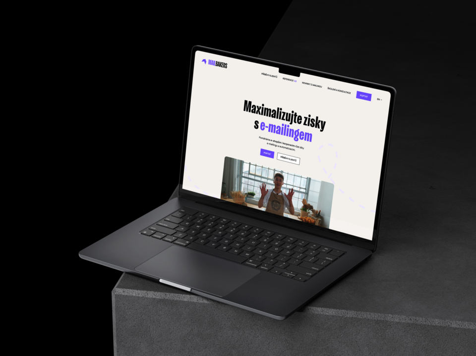Černý notebook na stole zobrazuje webovou stránku zaměřenou na maximalizaci zisků pomocí e-mailového marketingu. Moderní kancelářské prostředí dotváří atmosféru.