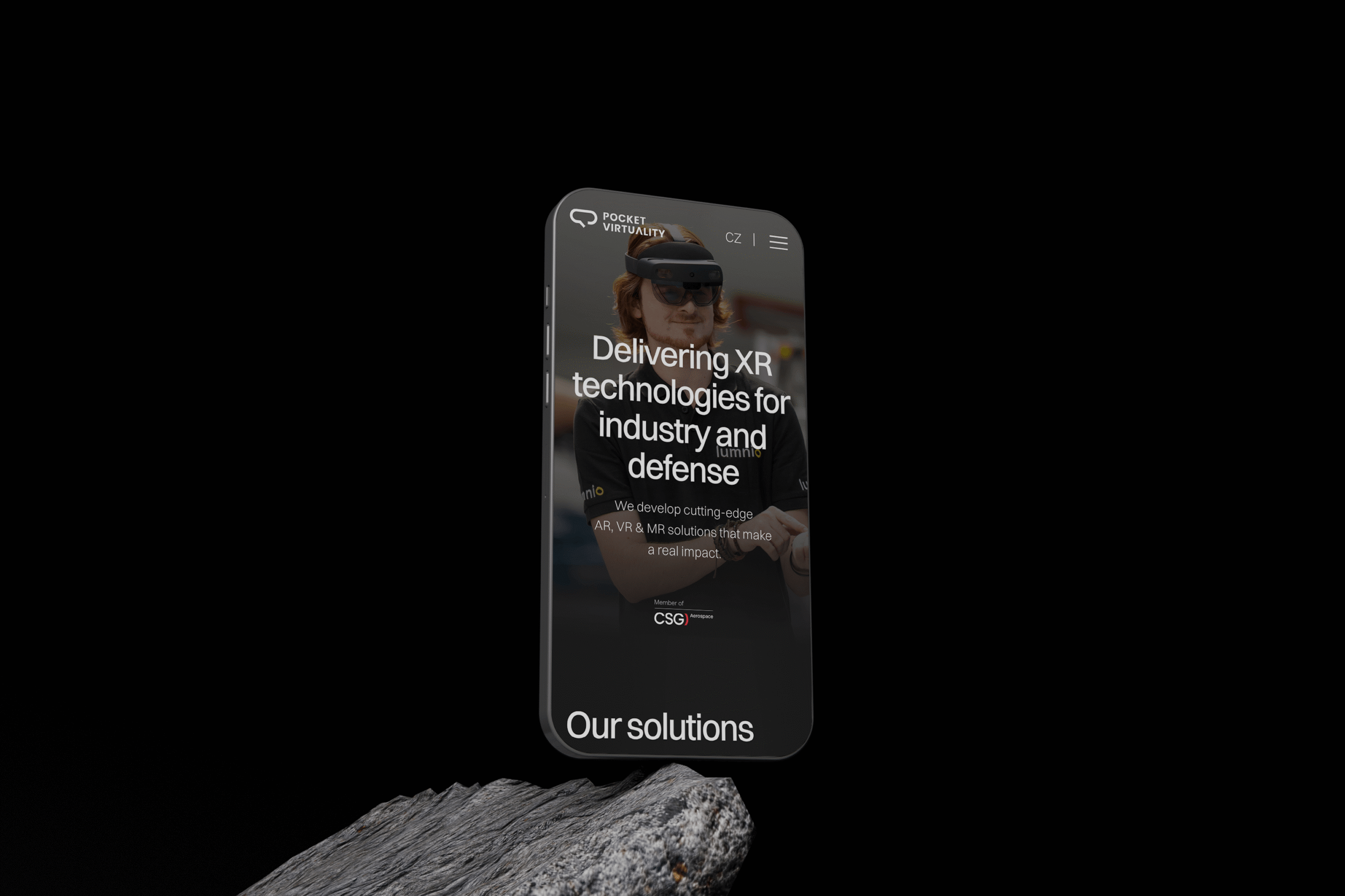 Smartphone zobrazuje XR technologie pro průmysl a obranu na tmavém pozadí.