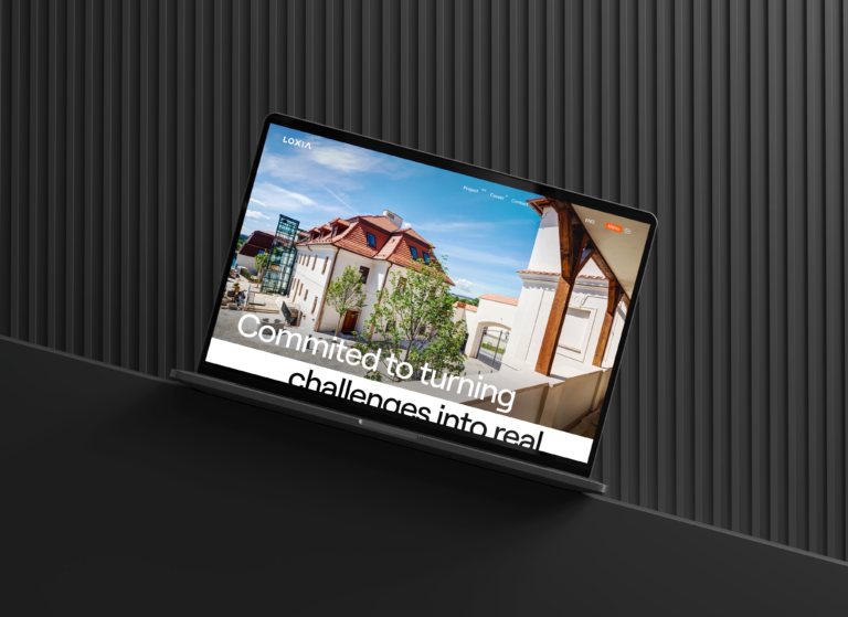 Notebook zobrazuje webovou stránku s moderními architektonickými budovami a stylovým designem Nabídka zahrnuje kreativní exteriérová řešení a inovativní koncepty