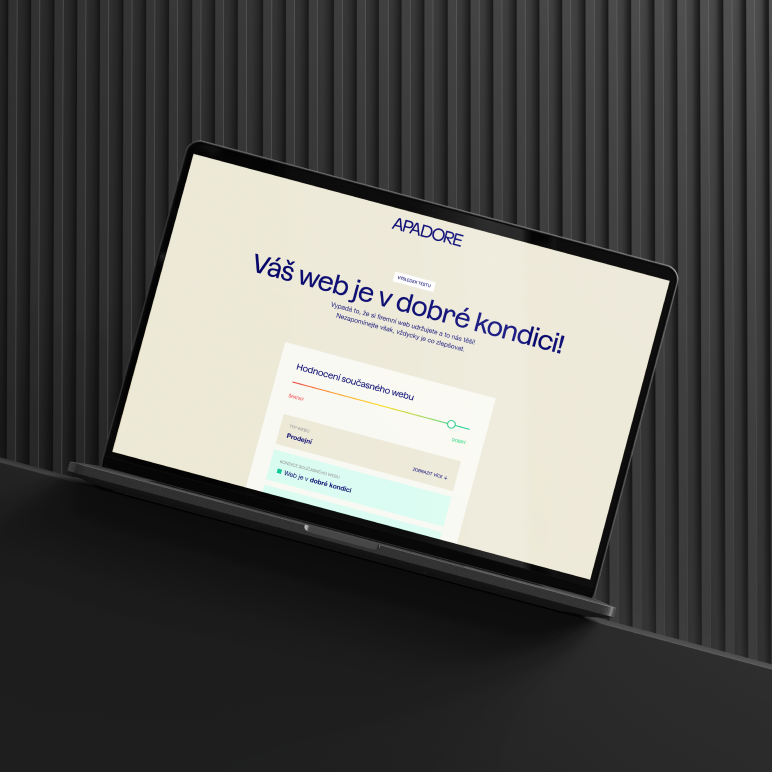 Notebook na tmavém pozadí zobrazuje webovou stránku s bílou obrazovkou a modrým textem Váš web je v dobré kondici a názvem Apadore nahoře.